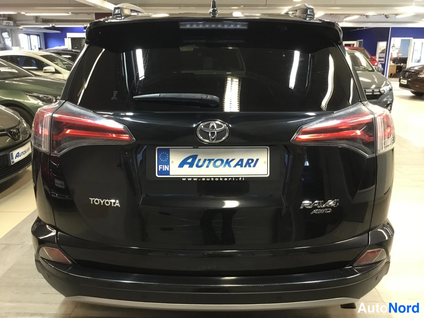 Takaa: Mustan Toyota RAV4:n takanäkymä, AWD-merkintä takaluukussa ja Autokari-kilpi.