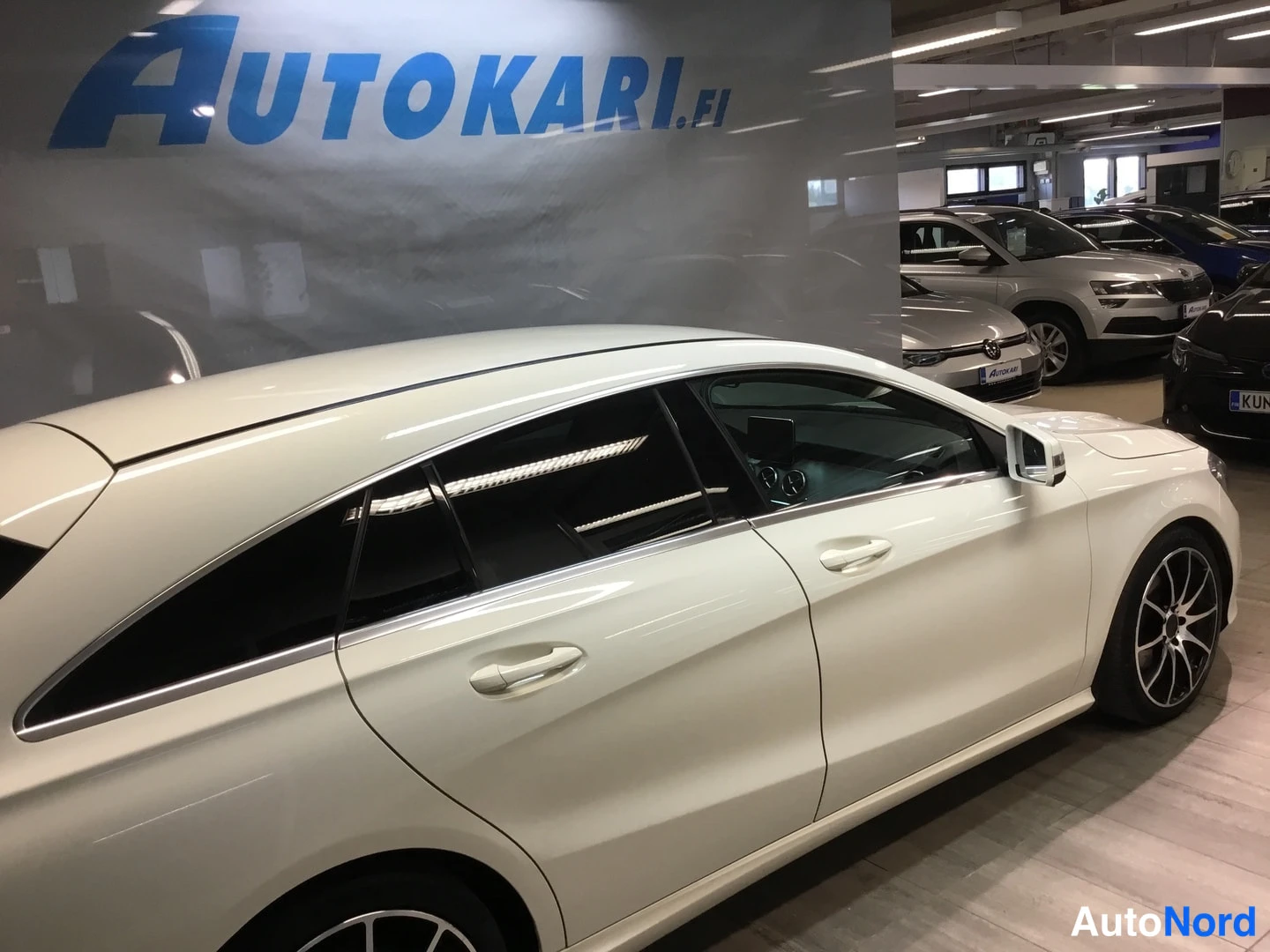 Sivulta: Valkoisen farmariauton sivuprofiili autonäyttelytilassa.
