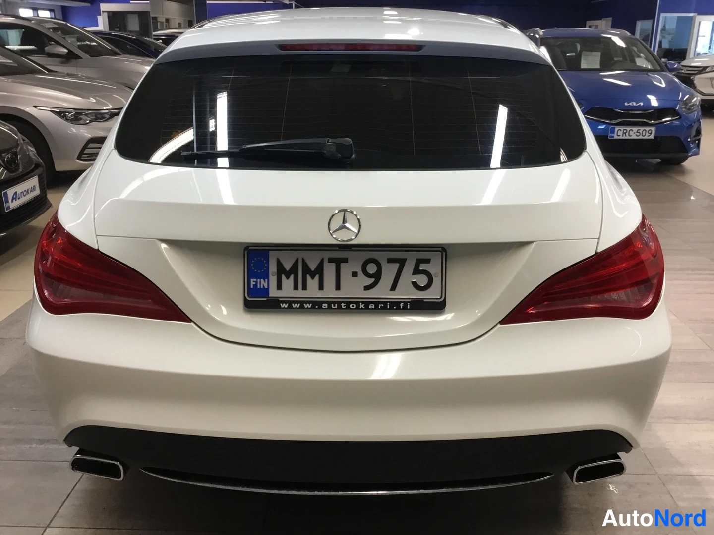 Takaa: Valkoisen Mercedes-Benzin takaosa suoraan takaa, näkyvät takavalo, takalasi ja rekisterikilpi.