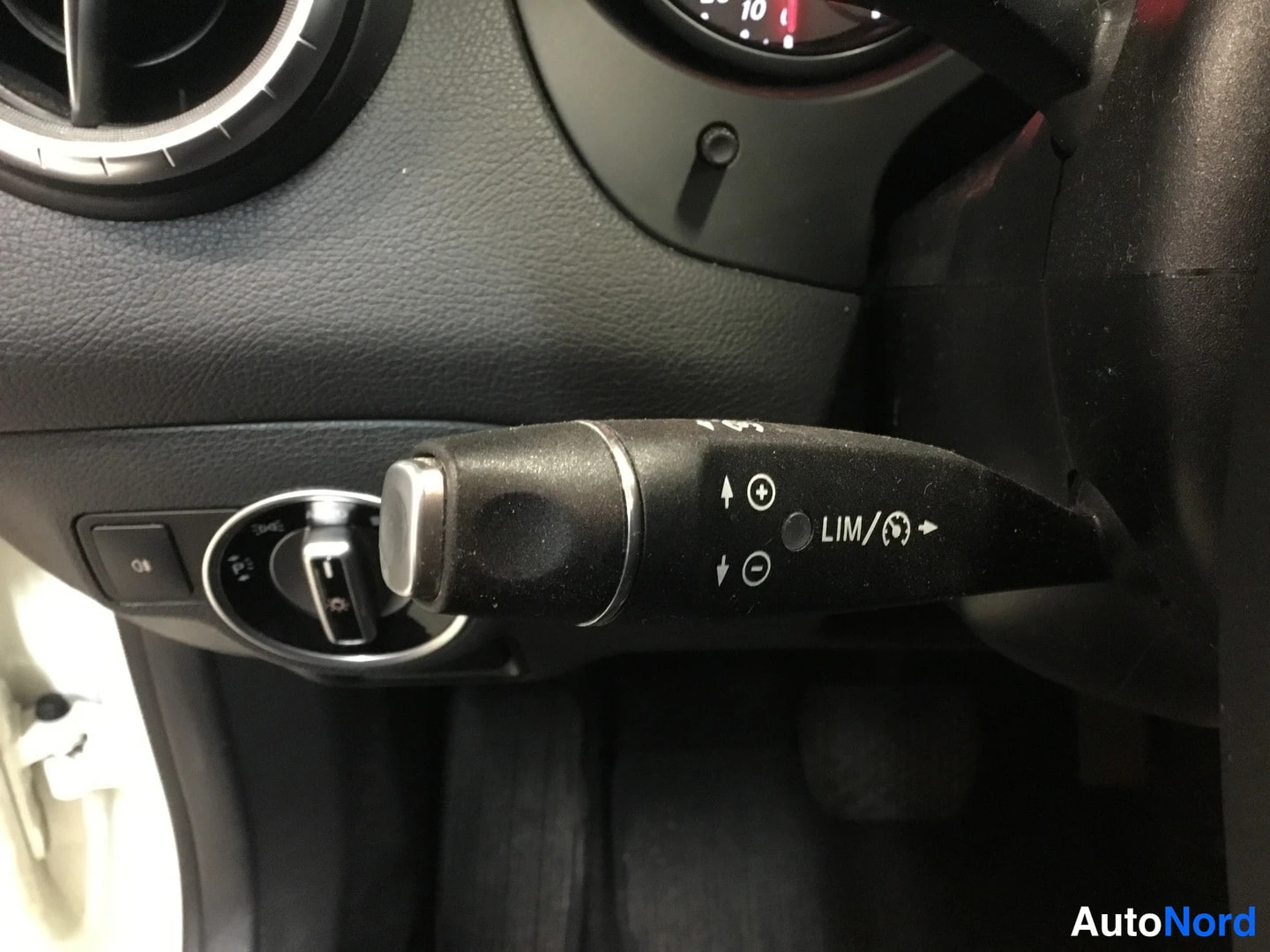 Yksityiskohta: Nopeudensäätövivun (cruise control) lähikuva ohjauspyörän takana, vivussa merkinnät LIM ja rajoitinsymboli.