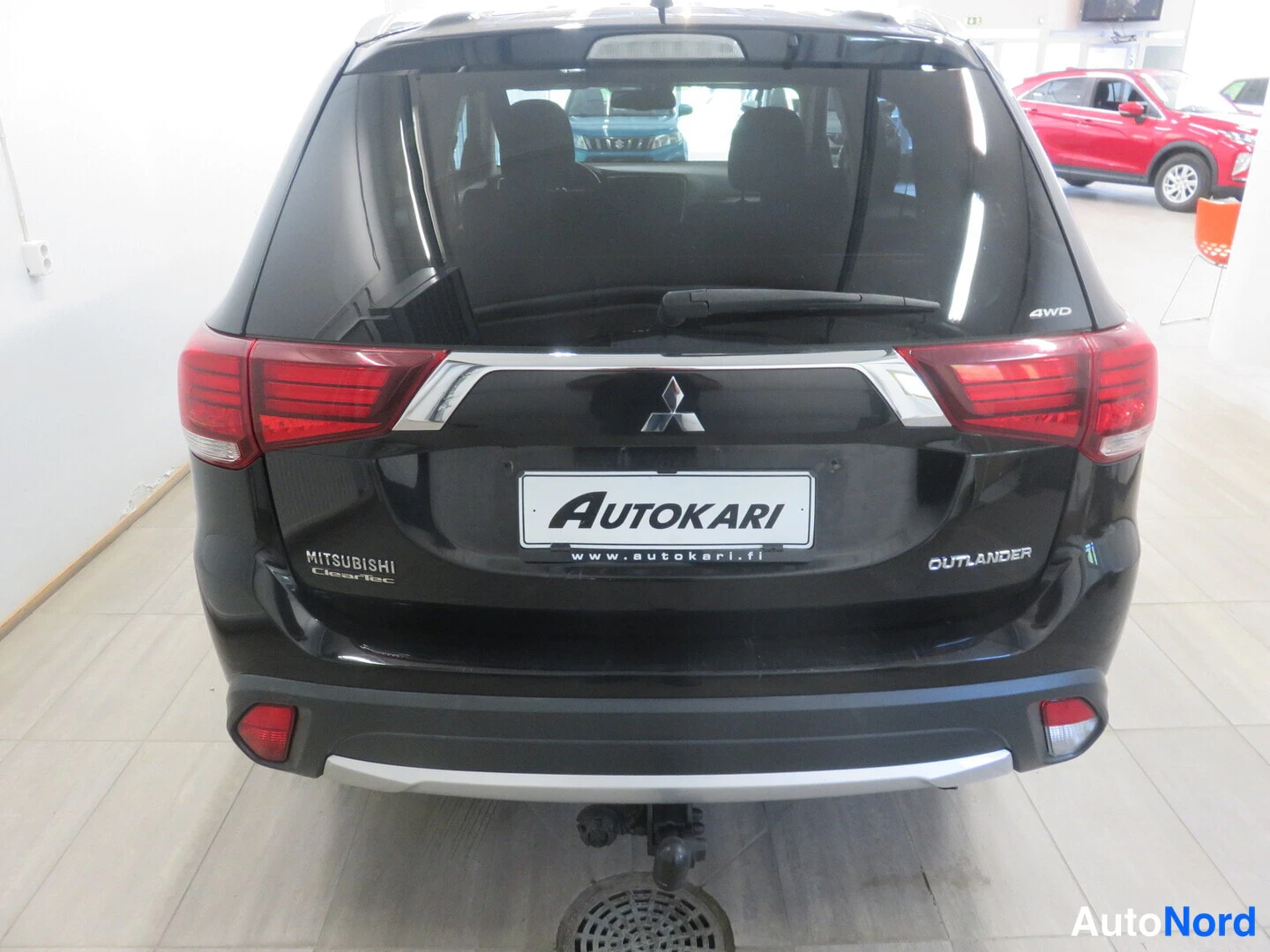 Takaa: Mustan Mitsubishi Outlanderin takaosa suoraan takaa, Mitsubishi- ja OUTLANDER-tekstit, Autokari-tunnus sekä MITSUBISHI ClearTec-teksti näkyvät.