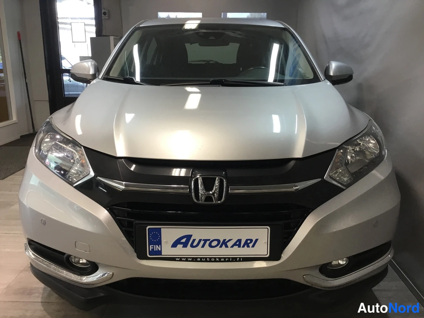 Edestä: Hopeanvärinen Honda HR-V edestä, kuva myymälätilassa; etusäleikkö ja Honda-merkki näkyvät.