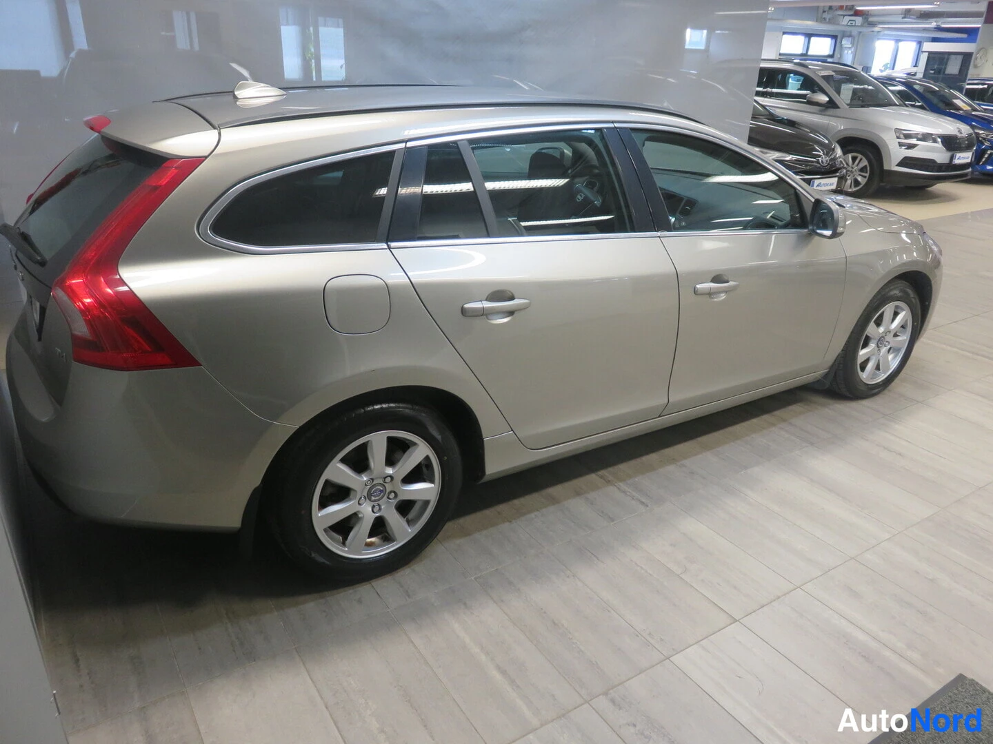 Sivulta: Volvo V60 -farmarin vasen kylki sisätiloissa, hopeanvärinen kori ja viisipaikkaisen korin sivulinjasto.