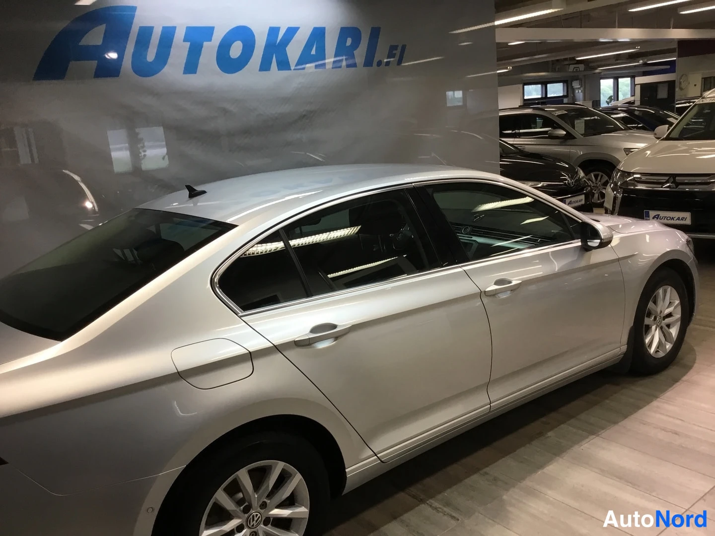 Sivulta: Hopeanvärinen Volkswagen Passat -sedan sivulta sisätilassa.
