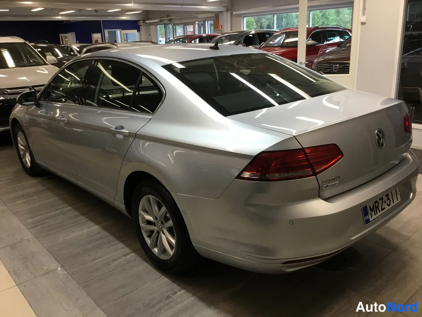 Takaviisto: Hopeanvärinen Volkswagen Passat -sedan kolme neljäsosaa takaa, rekisterikilpi.
