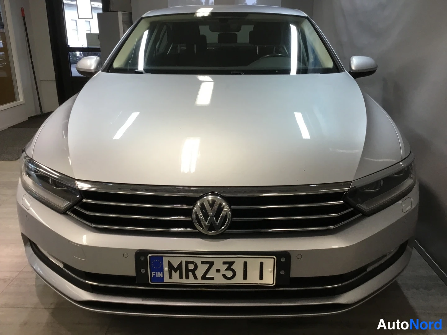 Edestä: Volkswagenin etupää edestäpäin; hopeanharmaa kori, VW-tunnus jäähdyttimen säleikössä ja suomalainen rekisterikilpi.