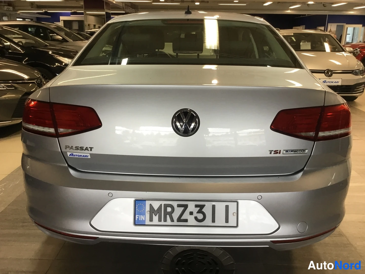 Takaa: Auton takapää suoraan takaa; hopeanharmaa kori, VW-tunnus, PASSAT- ja TSI BLUEMOTION-merkit sekä rekisterikilpi.