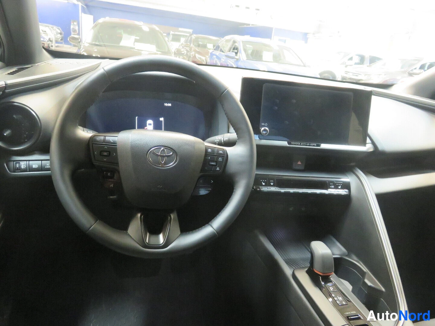 Edestä: Toyota-ohjauspyörä, digitaalinen mittaristo ja keskinäyttö, vaihteenvalitsin keskikonsolissa.