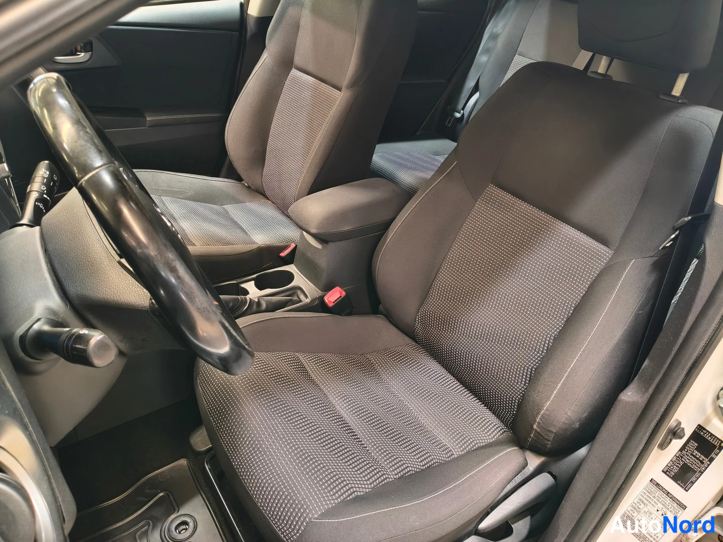 Yksityiskohta: Sisätilakuva Toyota Auriksesta: tummat kankiistuimet, etumatkustajan istuin ja osa takaistuimesta.