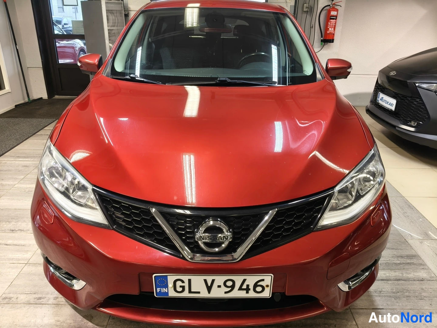 Edestä: Punainen Nissan, etupaneeli ja -kilpi edessä.