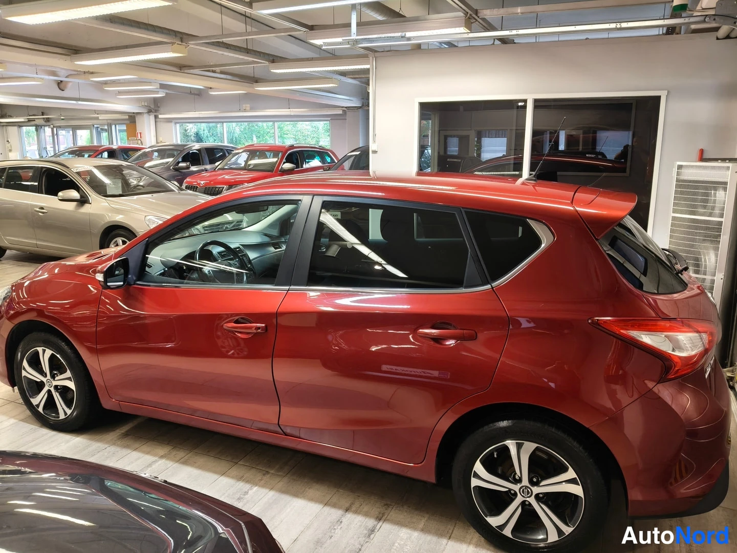 Takaviisto: Punaisen Nissanin takakolmasosa ja oikea kylki autosalissa.