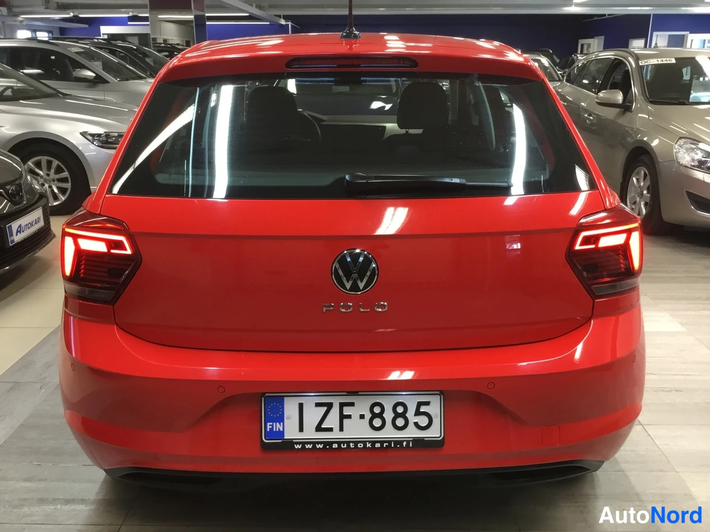 Takaa: Punaisen Volkswagen Polon takapää, POLO-tekni ja takavaloat syttyneinä, rekisteritunnus.