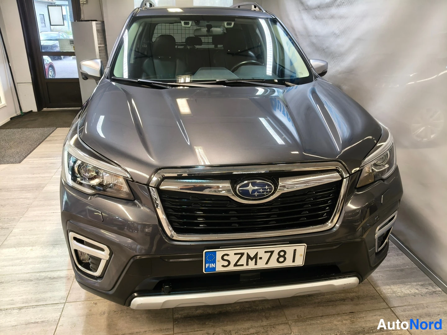 Edestä: Tummanharmaan Subaru Foresterin etupuoli suoraan edestä kuvattuna, rekisterikilpi.