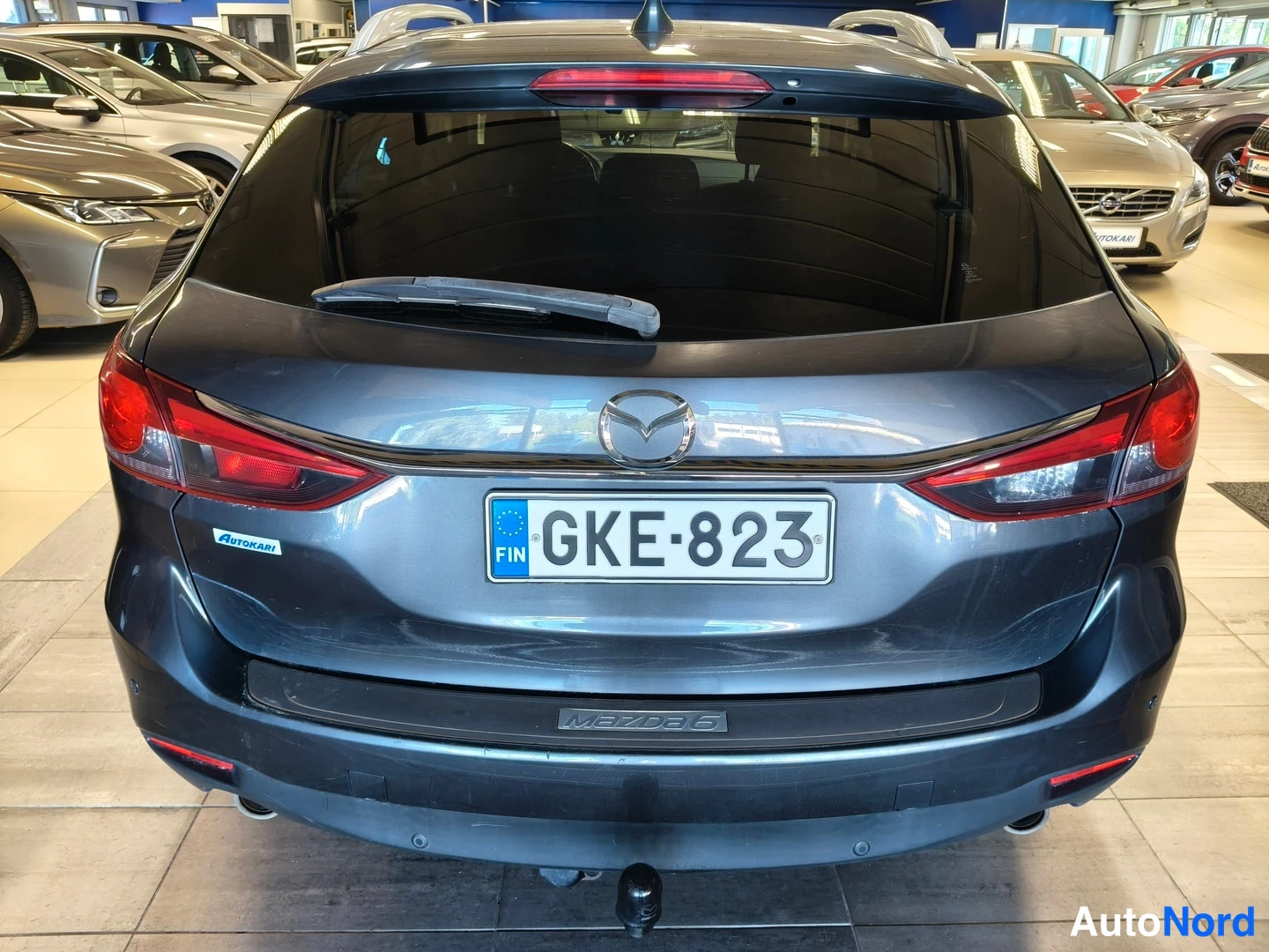 Takaa: Auton takanäkyvissä Mazda6-farmari, rekisterikilpi, vetokoukku kiinnitetty takapuskuriin.