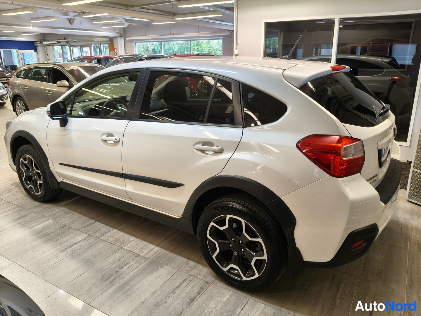 Takaviisto: Valkoisen Subaru XV -maasturin takaosa ja vasen sivu kulmasta kuvattuna myyntitilassa.
