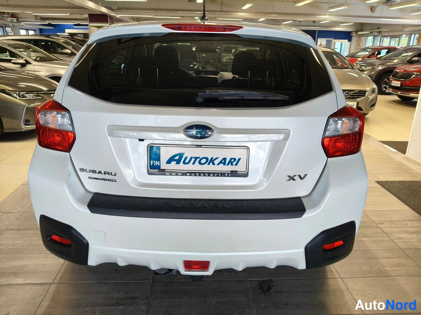 Takaa: Auton takaosa suoraan takaa: valkoinen Subaru XV, Autokari-tunnus kilvessä ja SUBARU-badge.