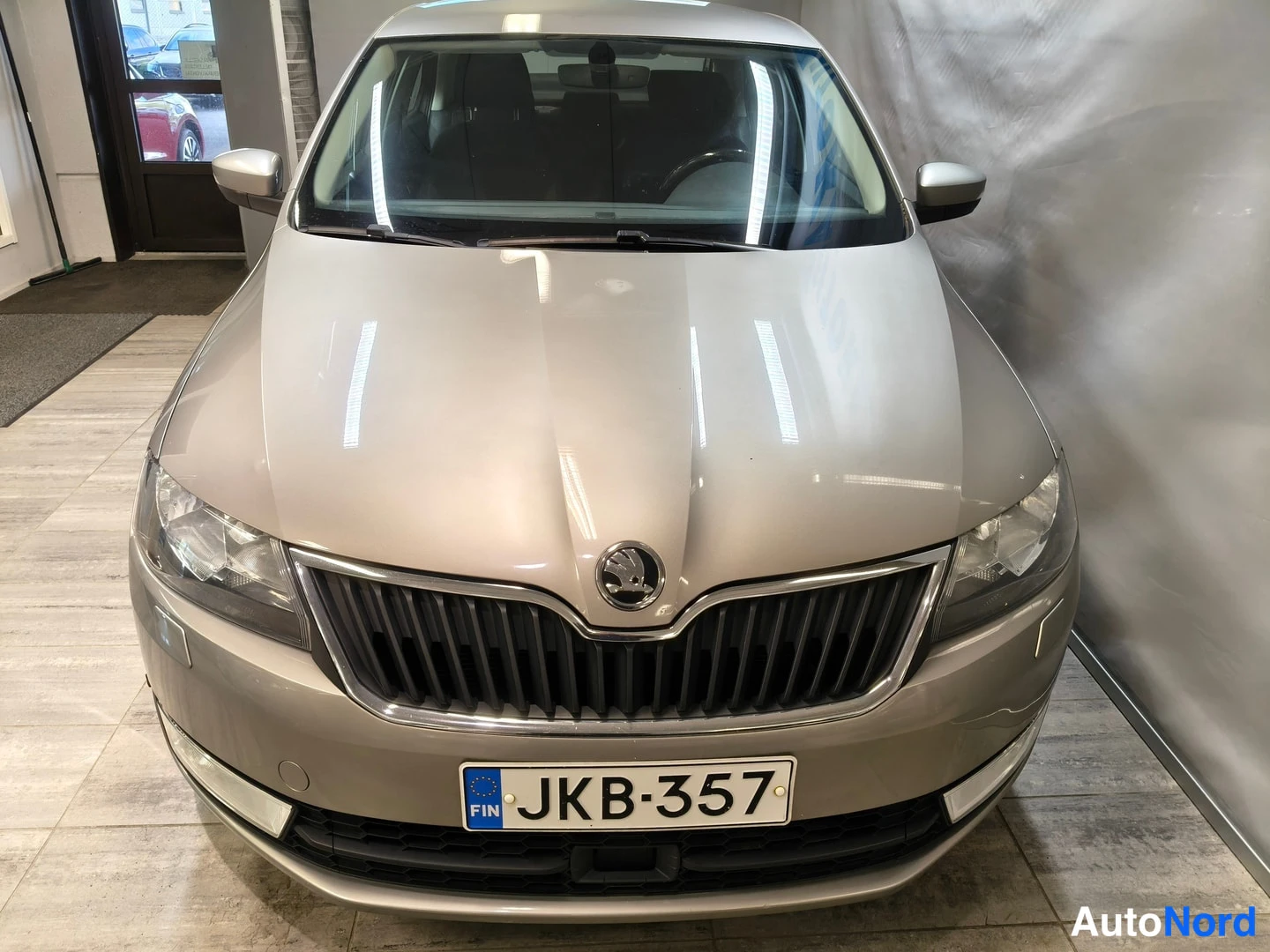 Edestä: Škoda Rapidin keula edestä päin, rekisterikilpi, vaaleanbeige kori.