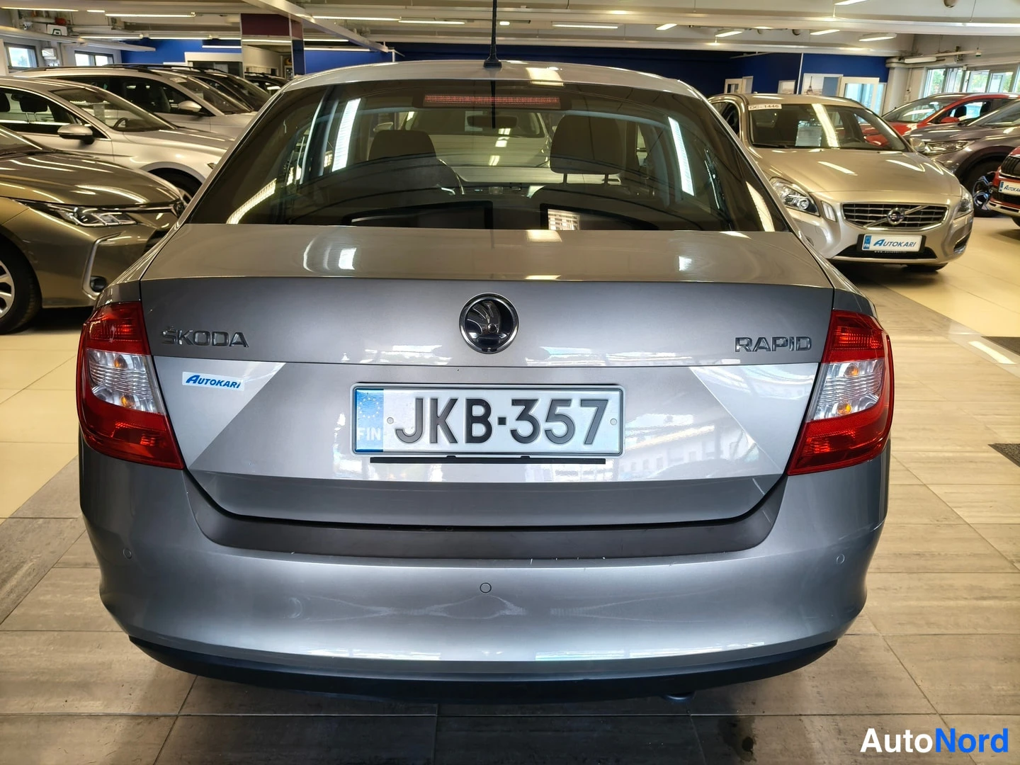 Takaa: Hopeanharmaa Škoda Rapid sedan takaa kuvattuna, rekisterikilpi, Skoda- ja Rapid-tekstit takaluukussa