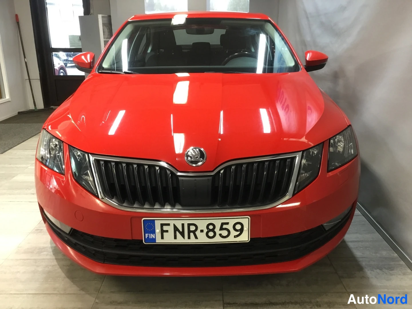 Edestä: Skoda Octavian etupäätä edestäpäin: punainen kori, kristallimainen etusäleikkö, logo ja rekisterikilpi.