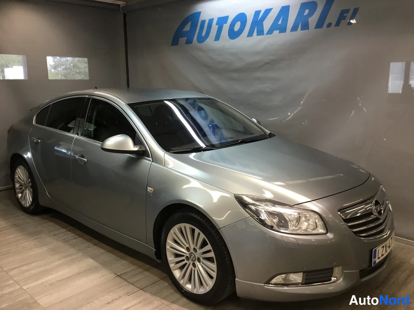 Etuviisto, nokka oikealle: Hopeanharmaa Opel Insignia -porssikäinen etuosa vasemmalta kuvattuna showroomissa.