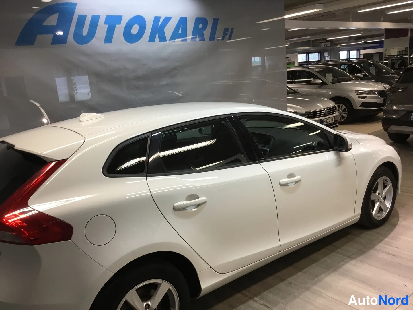 Takaviisto: White Volvo hatchback photographed indoors at a rear three-quarter angle from the right side.