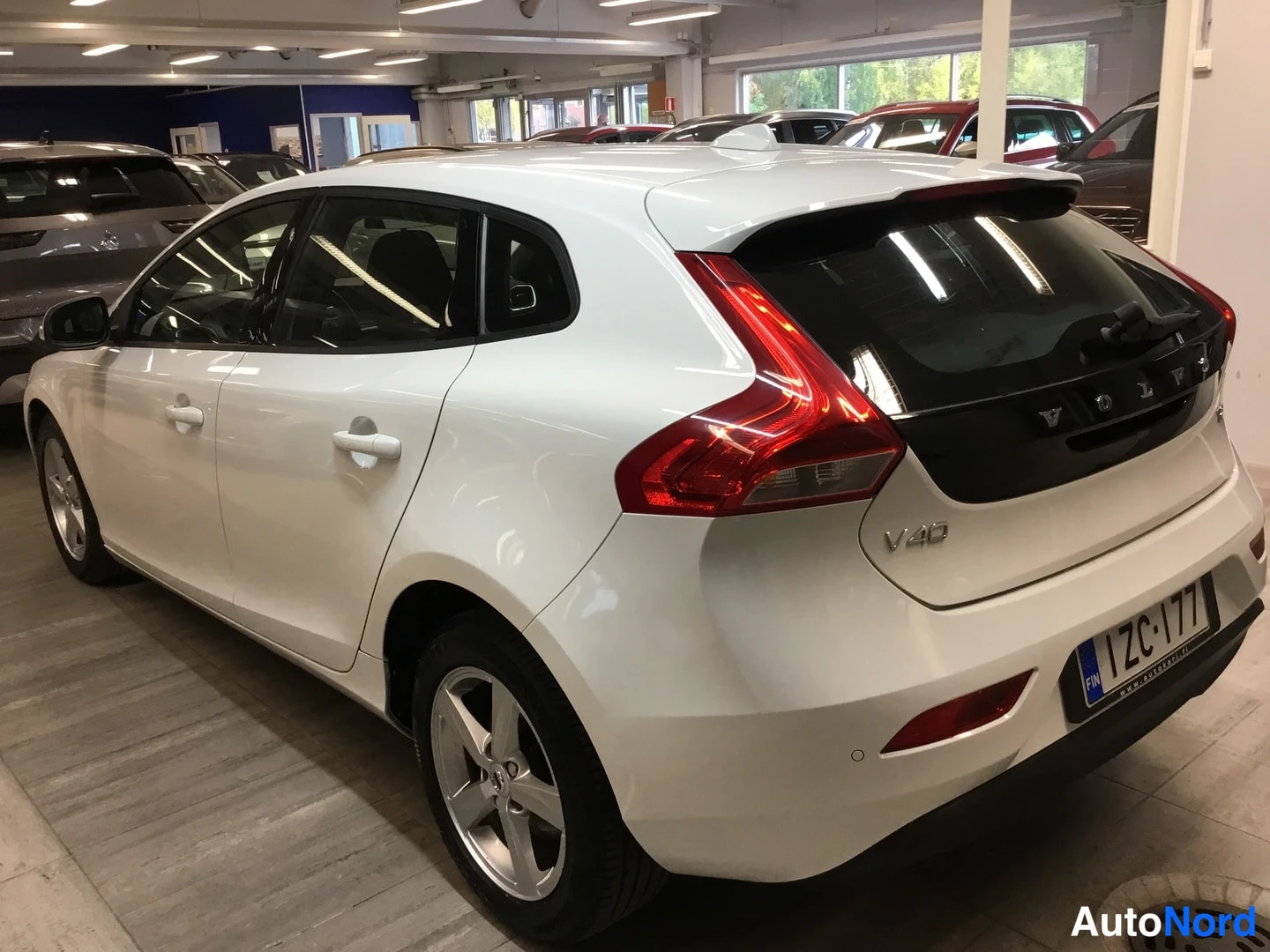 Takaviisto: White Volvo hatchback photographed indoors at a rear three-quarter angle from the left side; V40 badge and license plate visible.