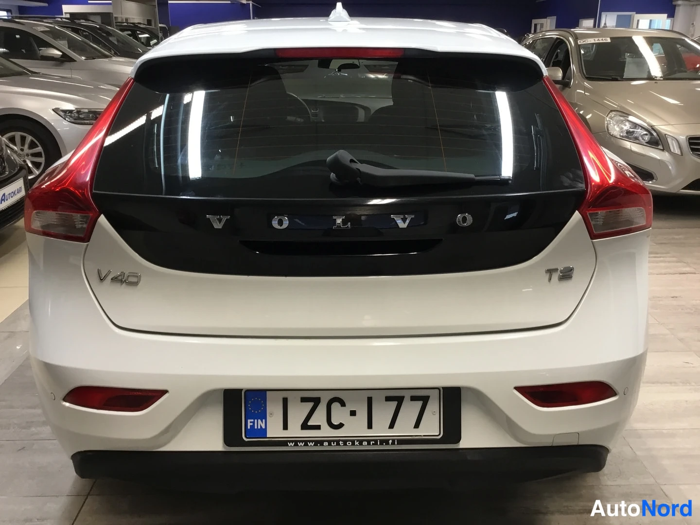 Takaa: Valkoinen V40 T2 -henkilöauto suoraan takaa showroomissa.