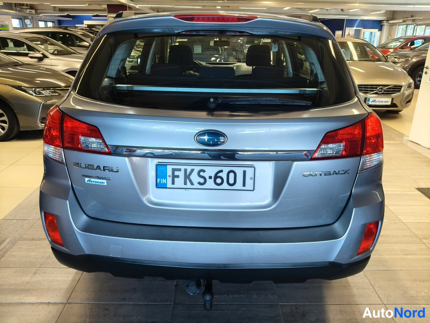 Takaa: Auton takaosa näytetään suoraan takaa; rekisterikilpi lukee ja takaluukissa SUBARU- ja OUTBACK-merkit.