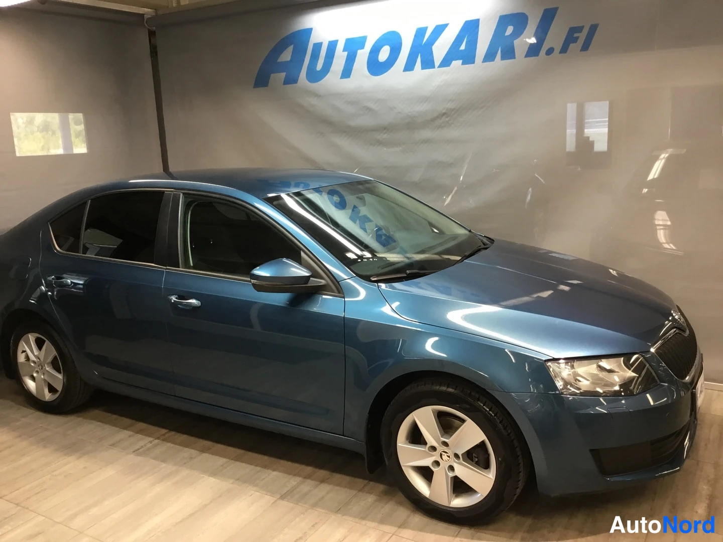Etuviisto, nokka oikealle: Sininen Škoda Octavia -henkilöauto etuosa oikealta näkyvässä kolmasosan kuvassa Autokari-hallissa.