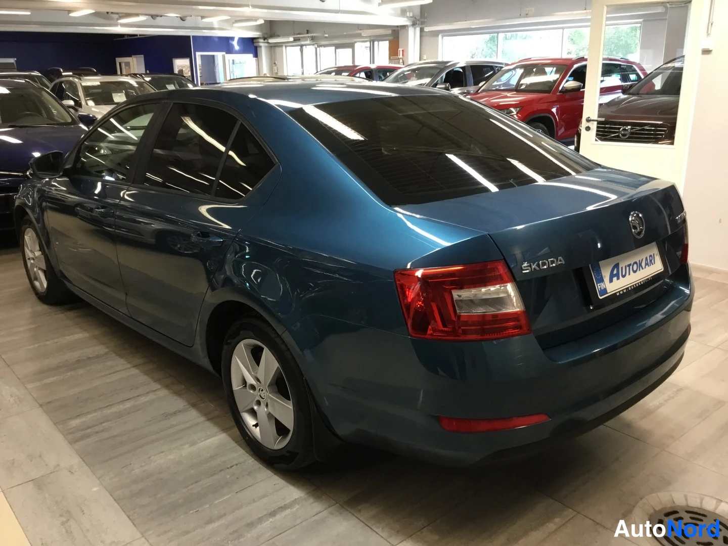 Takaviisto: Sininen Škoda Octavia -henkilöauto takakulma näkyvässä kolmasosan kuvassa, Škoda-tunnus ja Autokari-kilpi takaluukussa.