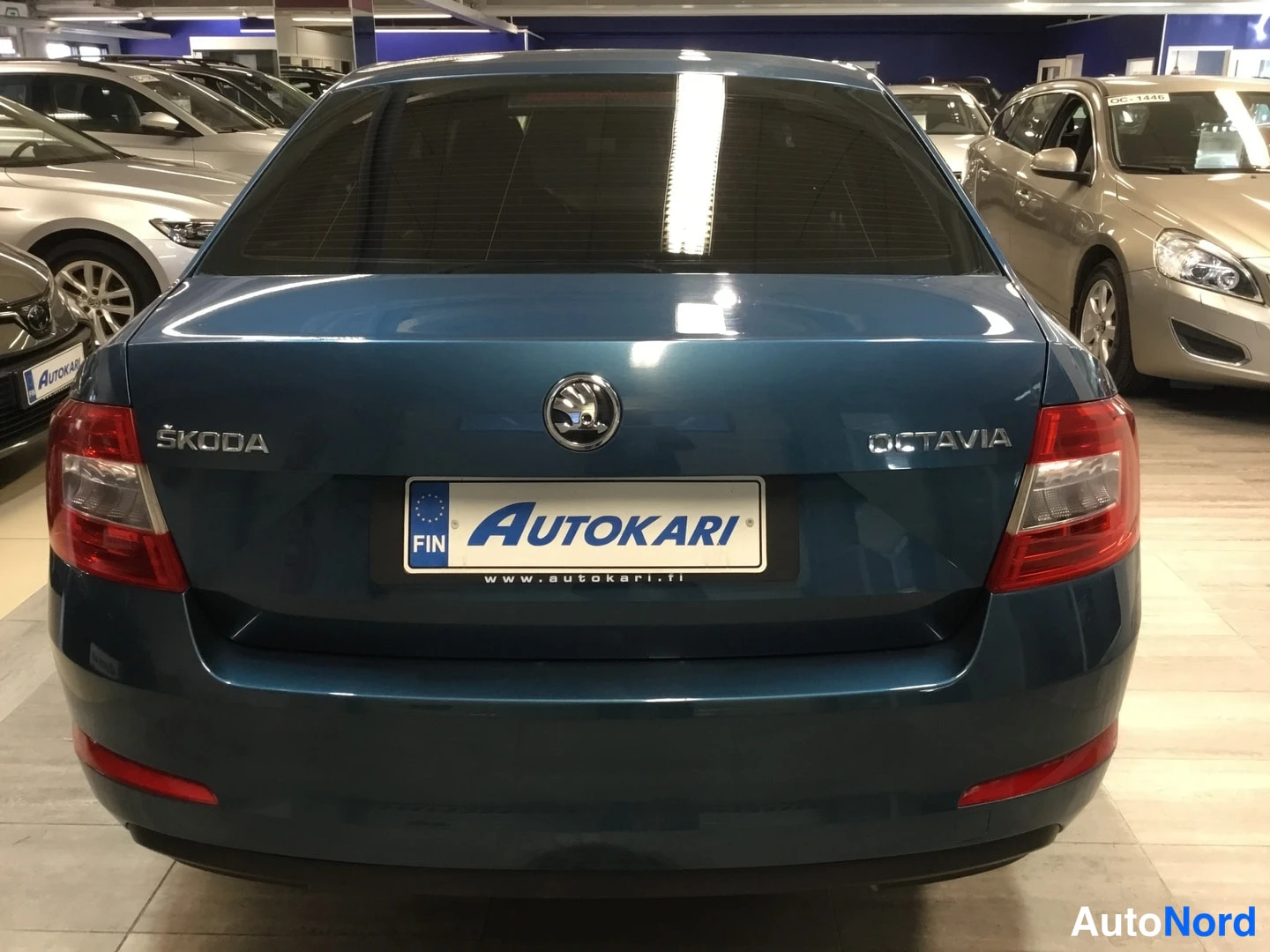 Takaa: Sininen Škoda Octavia takaa, peräkkä ja ŠKODA- ja OCTAVIA-merkinnät näkyvät takaluukussa autotallissa.