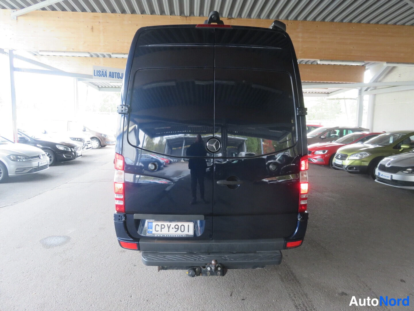 Takaa: Tummansininen Mercedes-Benz Sprinter -pakettiauto suoraan takaa päin, takana rekisteritunnus ja vetokoukku.