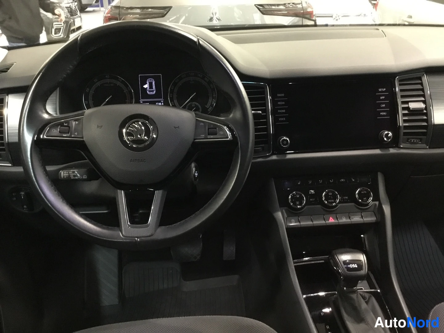 Edestä: Ohjaamo mittaristosta ja ruudusta kuvattuna: ohjauspyörä, infotainment-näyttö ja automaattivaihteiston valitsin.