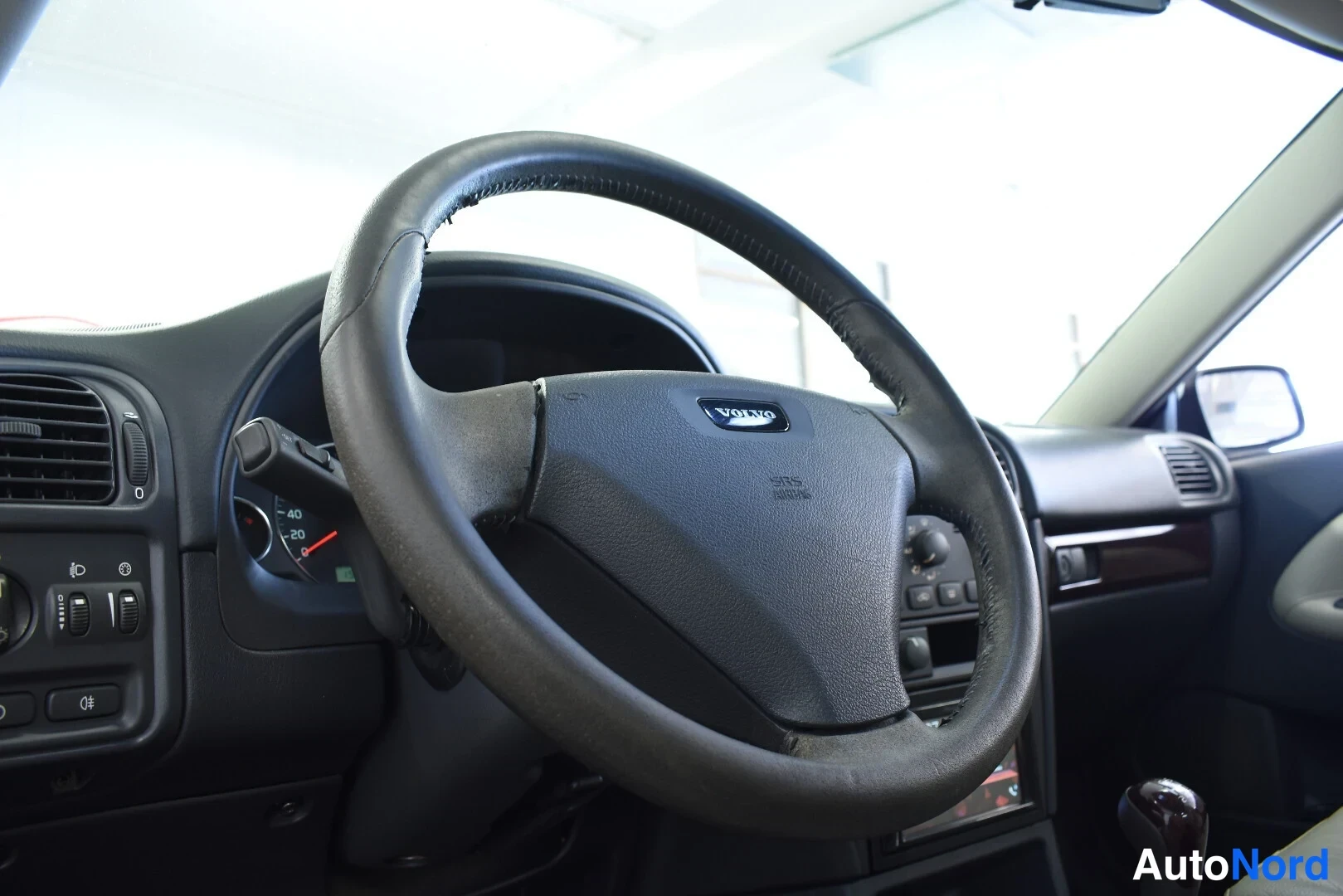 Muu: Lähikuva Volvo-ohjauspyörästä ja kojelaudan vasemmasta osasta.