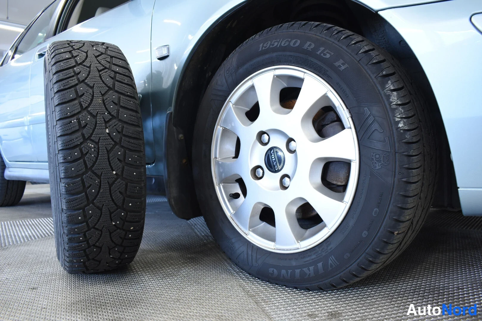 Muu: Nastarenkaat auton vieressä, pintojen 195/60 R 15 H ja Volvo-merkitty levyvannat.