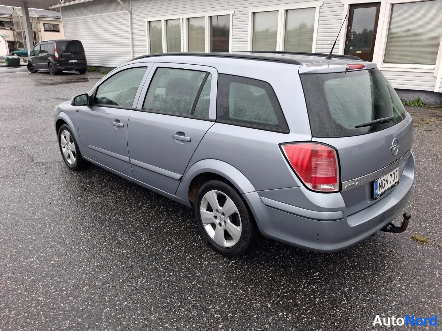 Takaviisto: Opel Astra Farmari takaviisto, vaalean harmaansininen, rekisteritunnus.