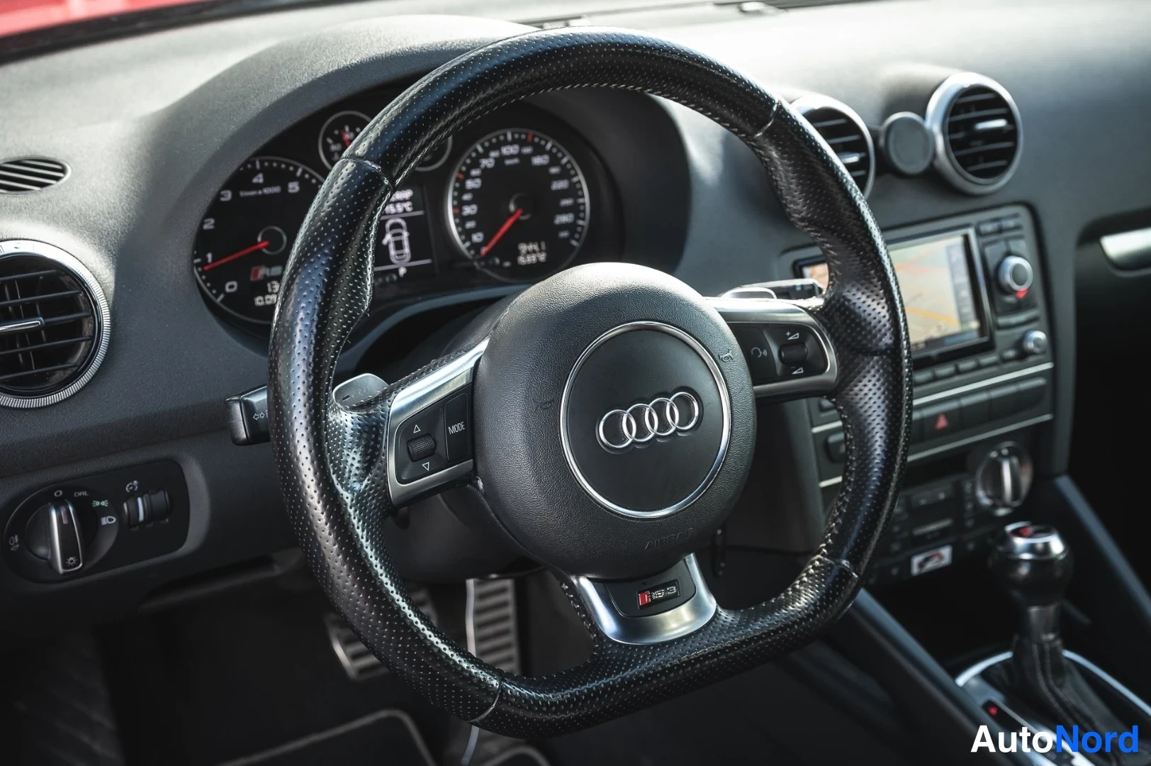 Muu: Sisäkuva: Audi-ohjauspyörä, kojelaudan mittarit ja radio-navigointilaite.
