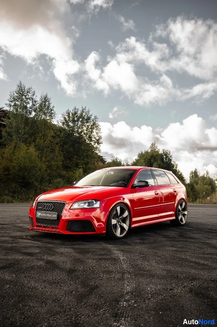 Etuviisto, nokka vasemmalle: Punainen Audi RS3 Sportback edestä vasemmalta kuvattuna, tummat vanteet.