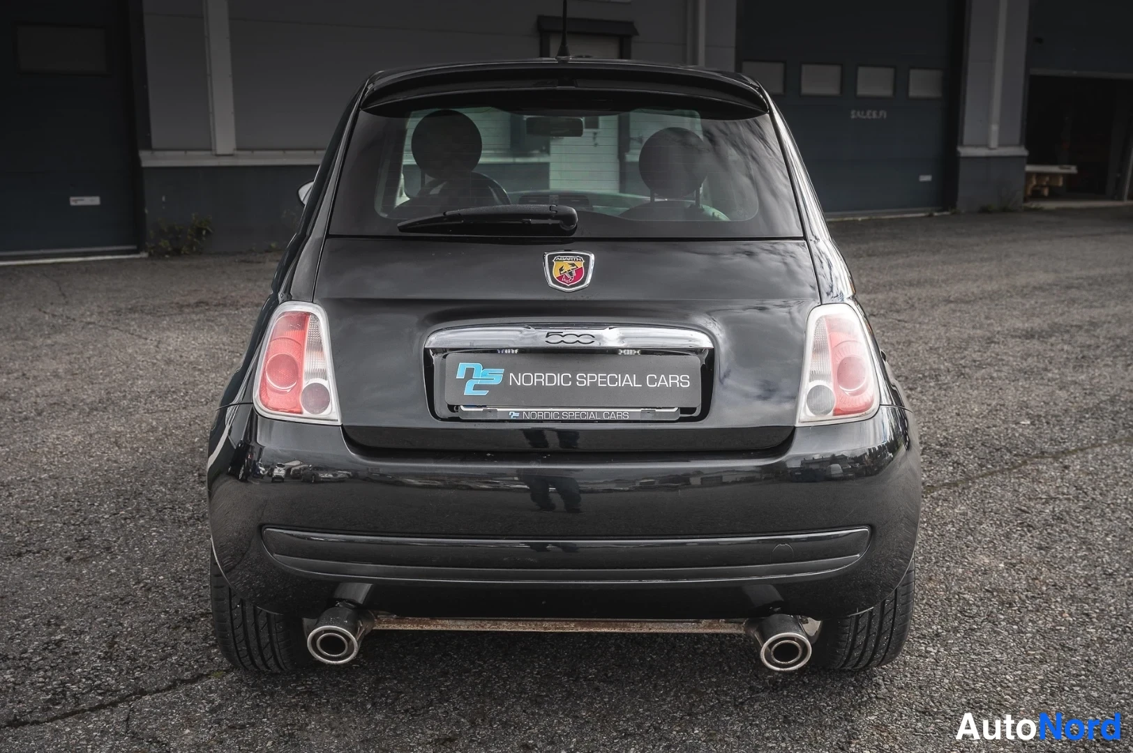 Takaa: Mustan Fiat 500:n suora takakuva, kaksiosaiset pakoputket ja takavalot näkyvissä.