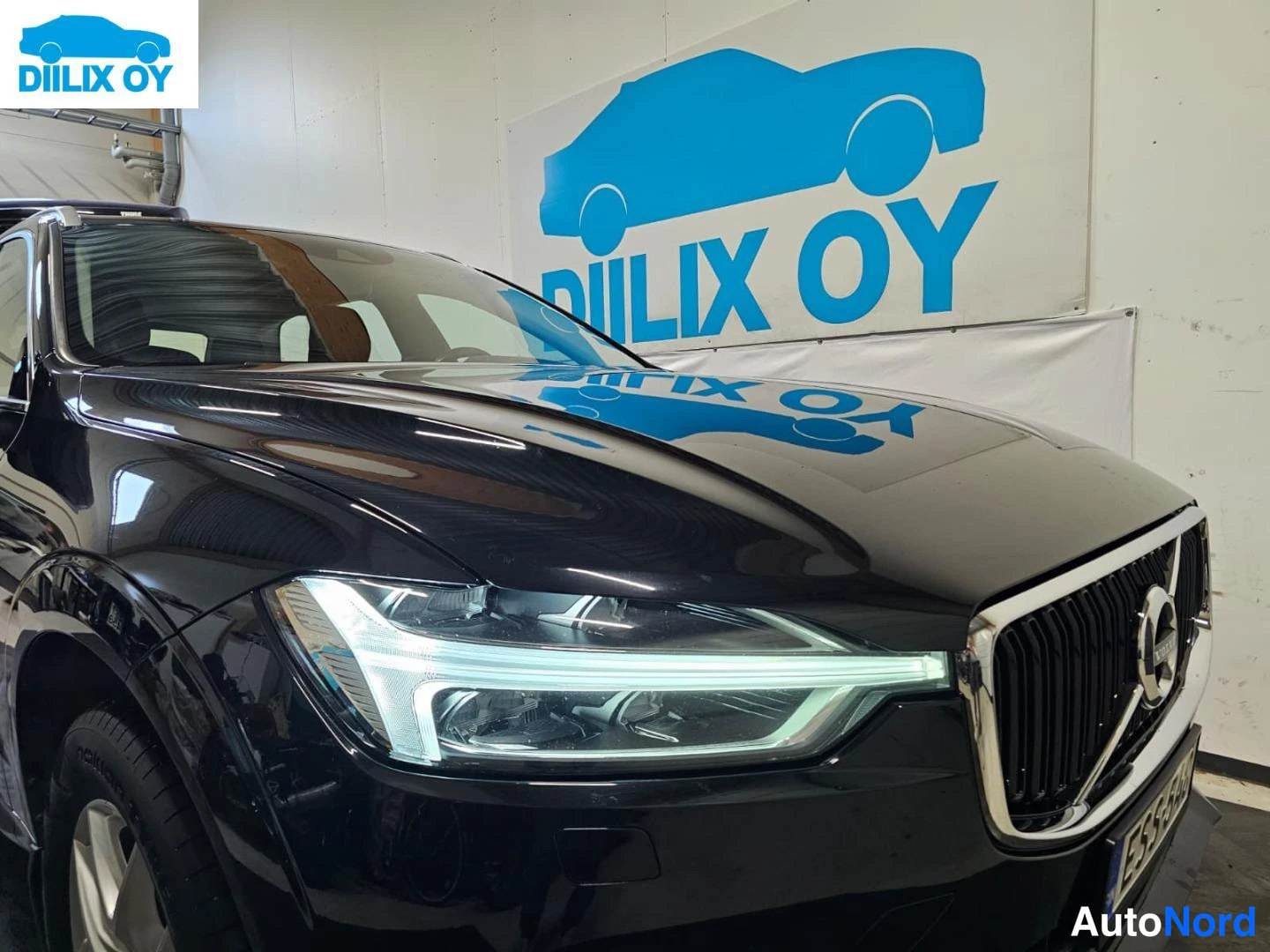 Etuviisto, nokka oikealle: Mustan Volvo XC60:n etukulma, etusäleikkö ja LED-etuvalot näkyvät sisätiloissa.