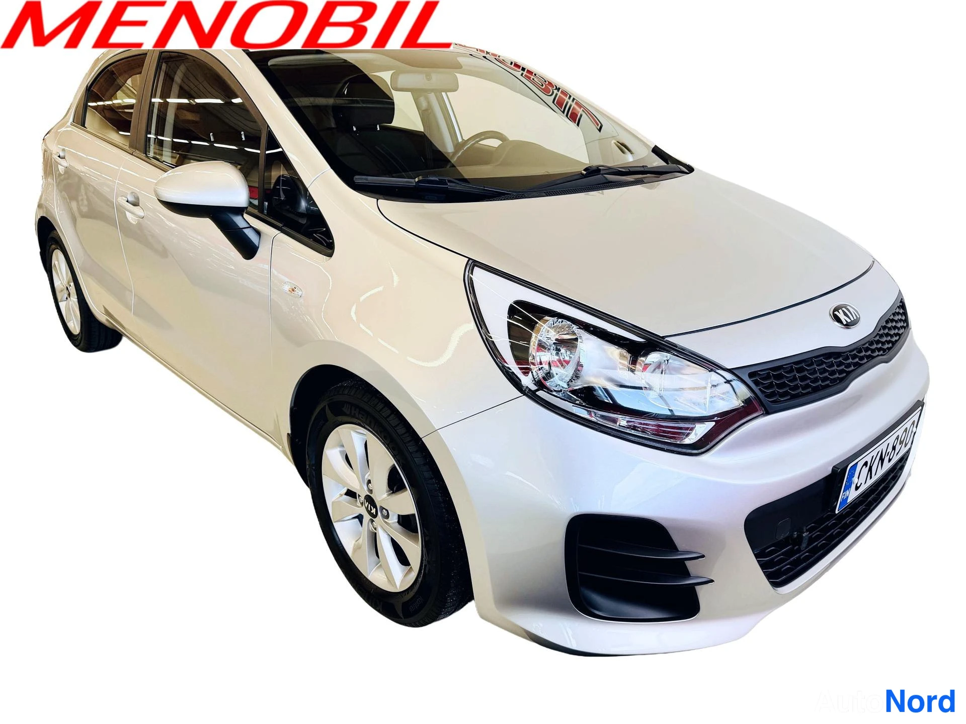 Etuviisto, nokka oikealle: Kia Rio -henkilöauto vaalean hopeisena kuvattu edestä vasemmalta, etusäleikkö ja ajovalot näkyvät oikealla.