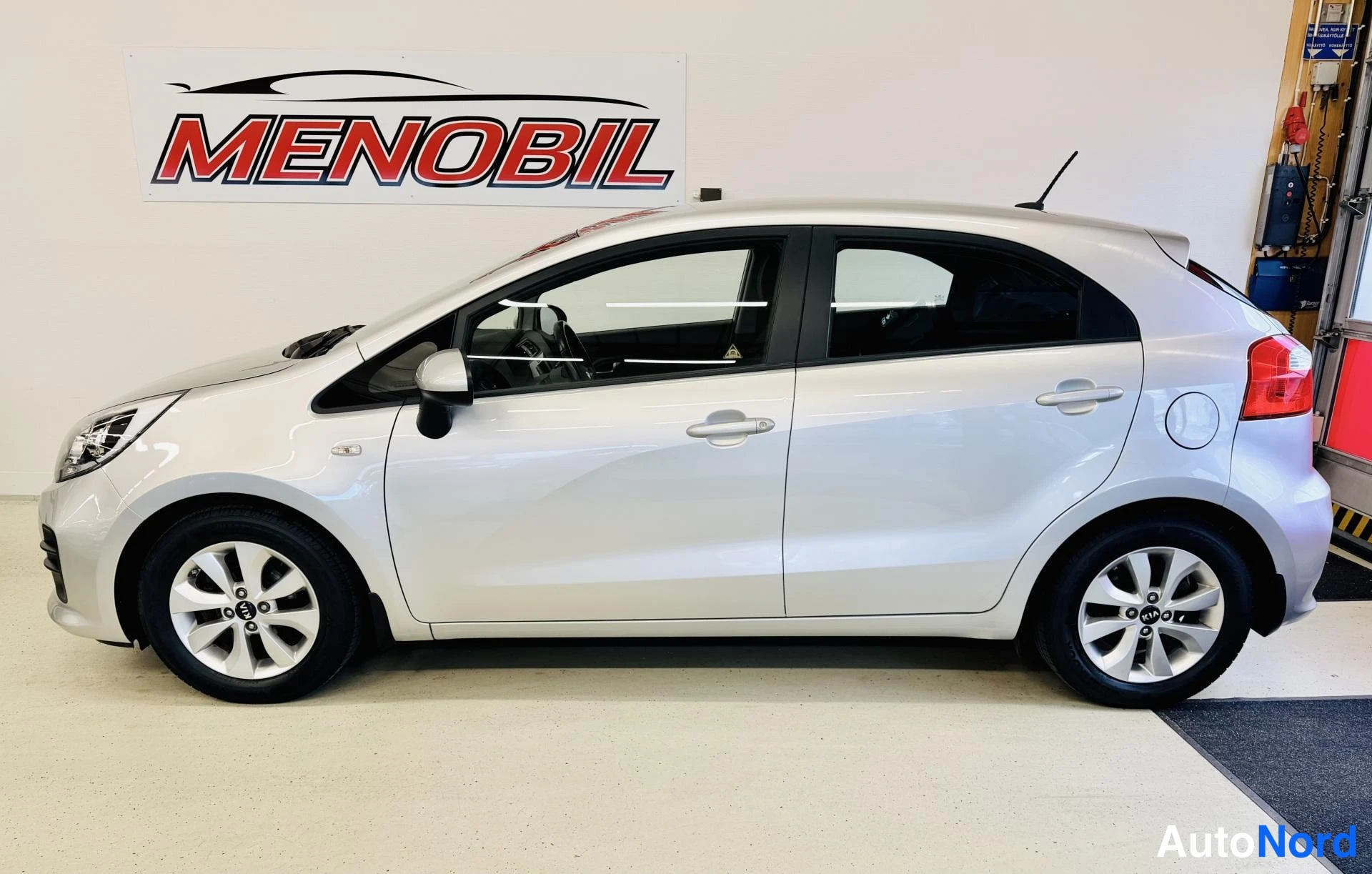 Sivulta: Kia Rio -henkilöauto vaalean hopeisena sivulta kuvattuna, viisiovinen viistoperä.