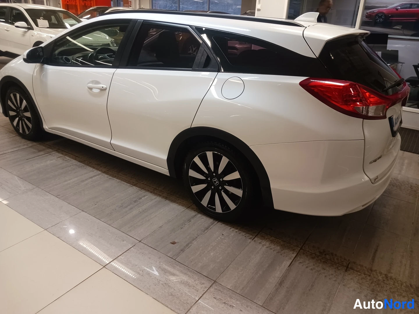 Takaviisto: Valkoinen Honda Civic Tourer takakulmasta, punaiset takavalot ja mustat kattokaaret näkyvät.