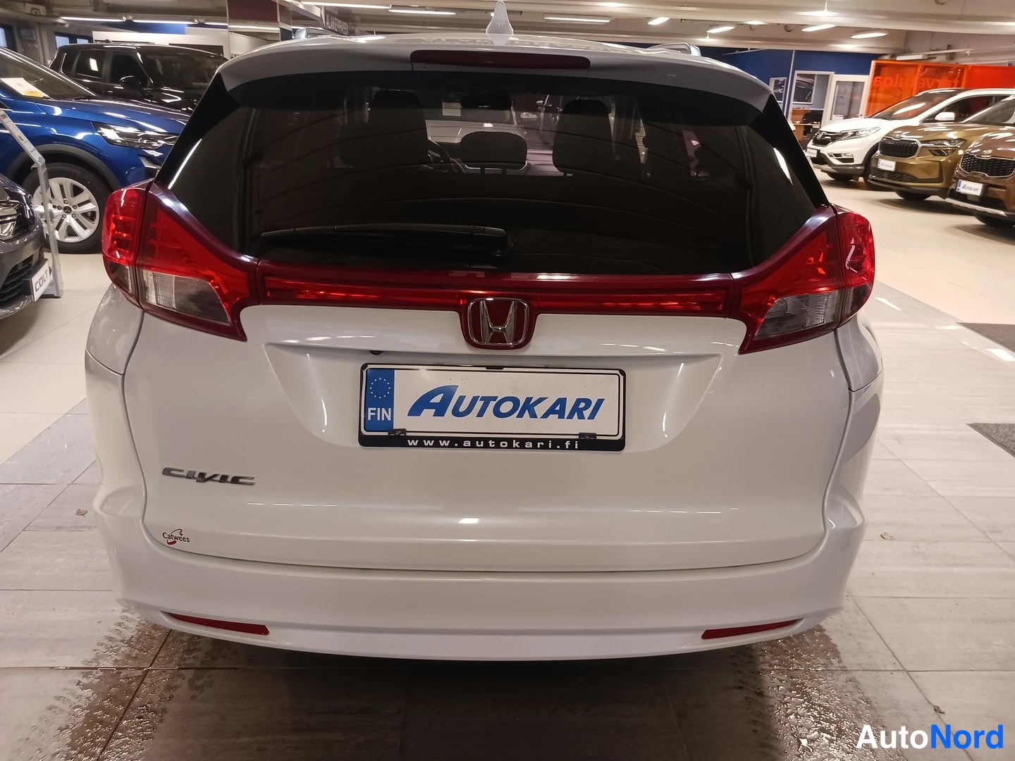 Takaa: Auton takaosa: valkoinen Honda Civic, punaiset takavalot, Honda-merkki ja rekisterikilven tilalla AUTOKARI-nimike.