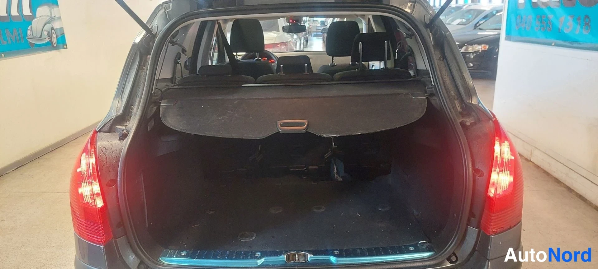 Takaa: Peugeot 308 farmarin takakontti avattuna, takavalot näkyvät.