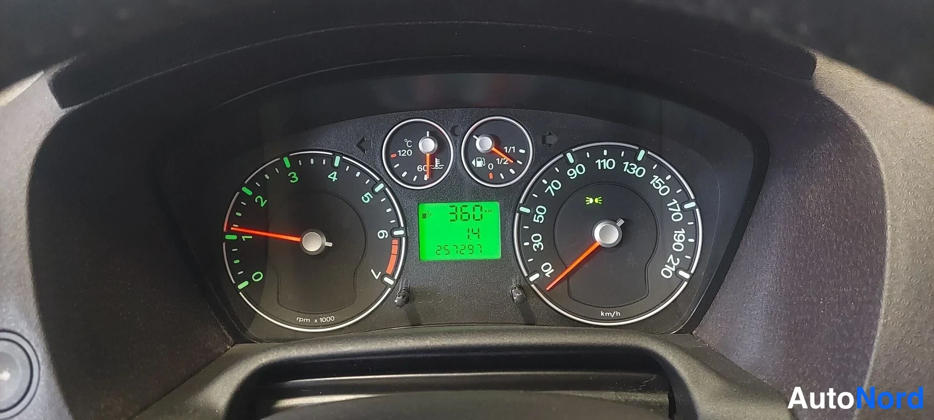 Muu: Mittariston lähikuva: kaasutin- ja nopeusmittari sekä vihreä näyttö, jossa lukee 257297 km ja huoltomerkintä.