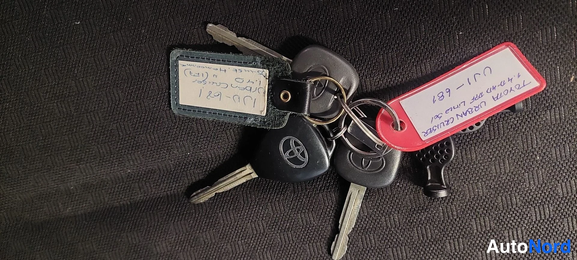 Muu: Avaimenperä kahdella Toyota-avaimella ja punainen avainnauha käsinkirjoitetuilla merkinnöillä.