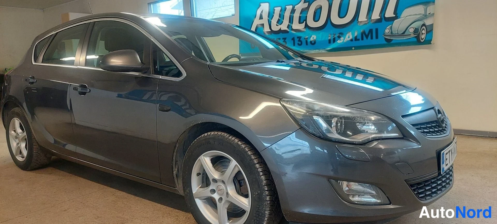 Etuviisto, nokka oikealle: Harmaa Opel Astra -henkilöauto kolmannelta sektorilta edestä oikealla sisätiloissa.