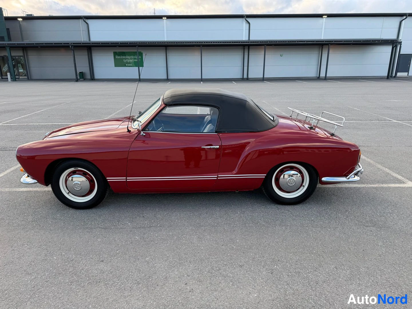 Sivulta: Punaisen tummanpunainen Volkswagen Karmann-Ghia -cabriolet sivusta kuvattuna, musta pehmeä katto ylhäällä ja takaosassa krominen matkatavarateline.