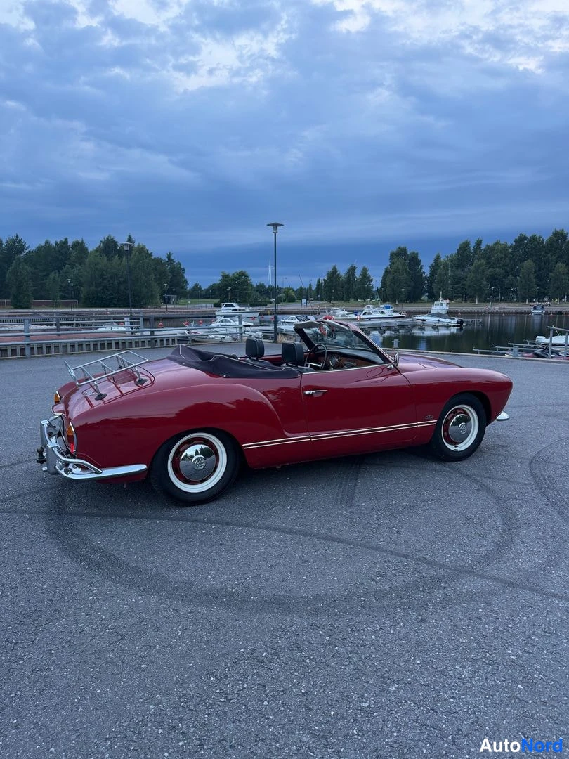Takaviisto: Tummanpunainen Volkswagen Karmann-Ghia -cabriolet takaosan kolmanneskäänteisestä vasen kylki näkyvissä, avonainen yläosa ja takana krominen matkatavarateline.